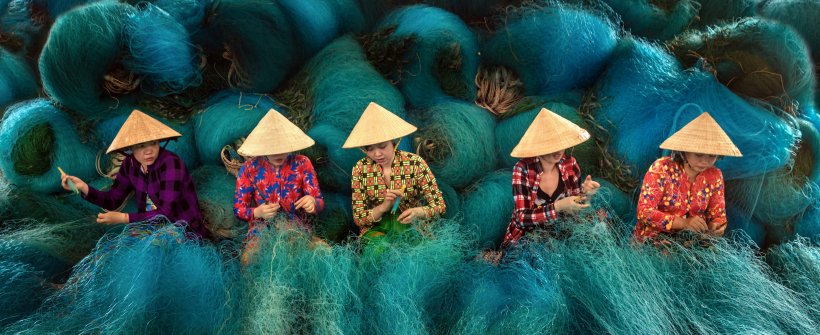 Vietnamese women are sitting repairing fishing nets